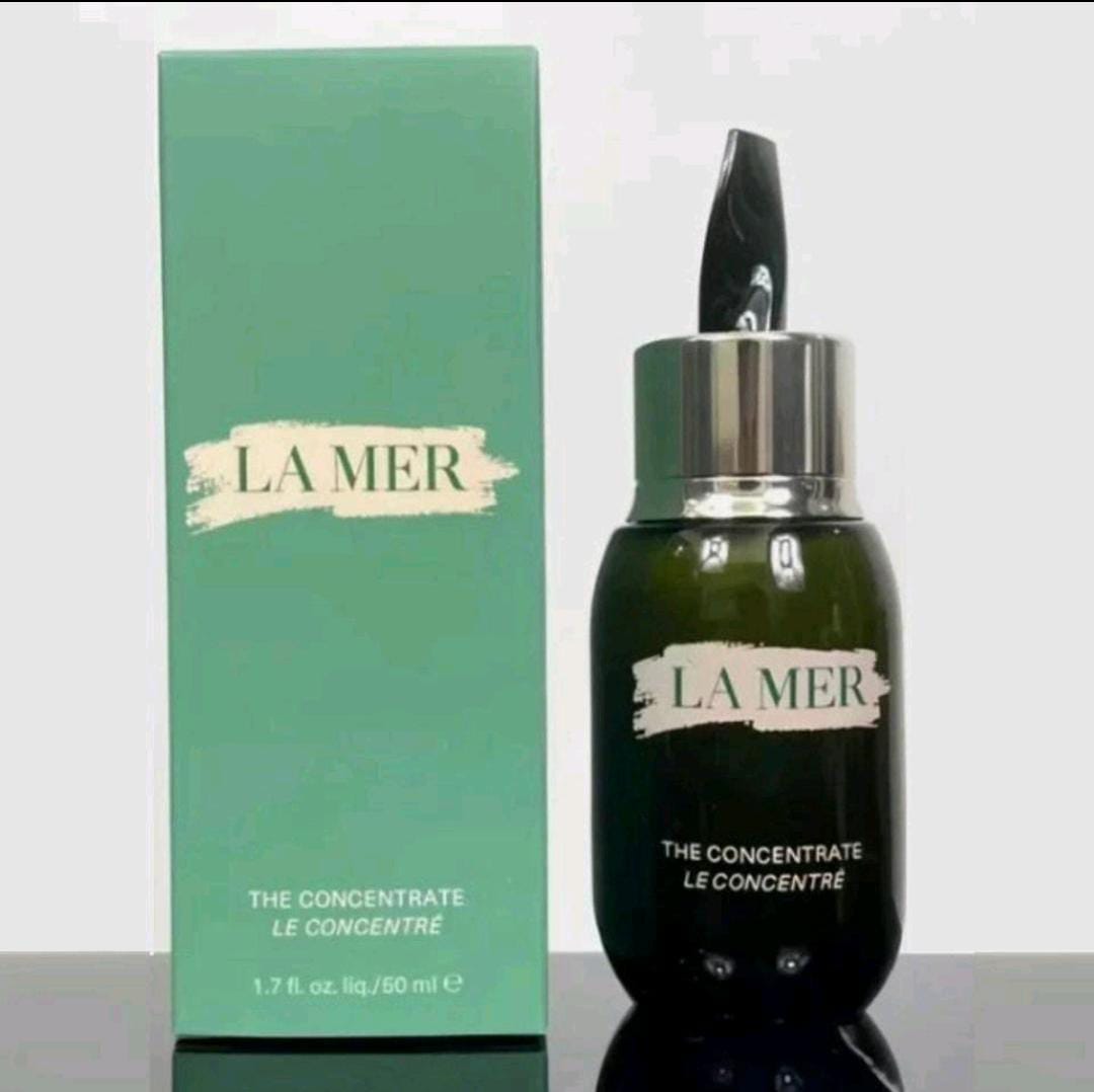 La Mer The Concentrate Le Concentrate skincare bottle and its matching mint green packaging box, displayed on a reflective surface against a light gray background.