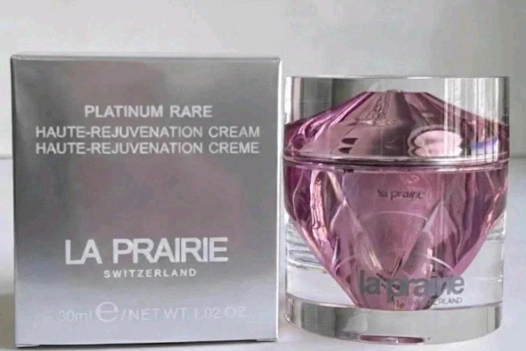 La Prairie Platinum Rare Haute-Rejuvenation Cream 30ml bottle next to its silver packaging box, featuring a faceted pink-purple crystal-like bottle and white text on a light gray background.