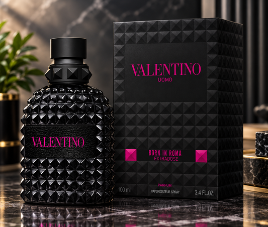 Valentino Uomo Born in Roma Extraordinaire perfume bottle and packaging box, both in black with pink lettering, displayed on a dark marble surface.